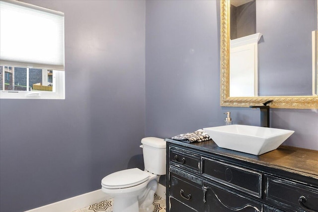 half bath with vanity, toilet, baseboards, and tile patterned flooring