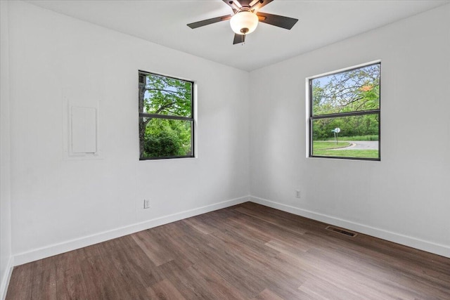 empty room with baseboards, ceiling fan, visible vents, and wood finished floors
