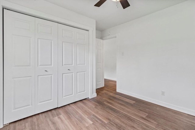 unfurnished bedroom featuring a closet, a ceiling fan, wood finished floors, and baseboards