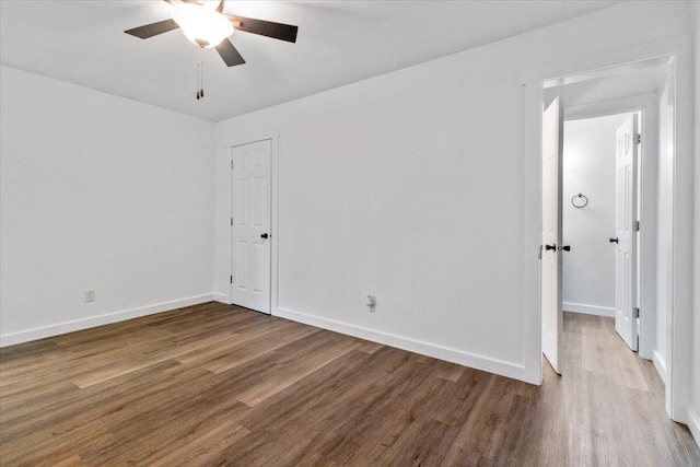 empty room with ceiling fan, baseboards, and wood finished floors