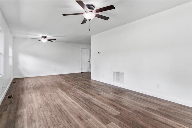 empty room with baseboards, a ceiling fan, visible vents, and dark wood finished floors