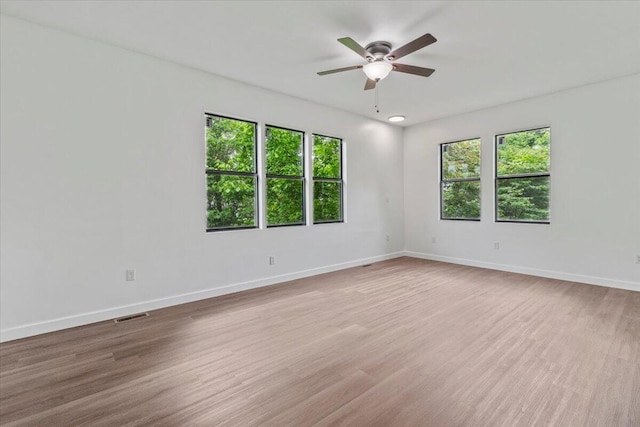 spare room with baseboards, visible vents, ceiling fan, and wood finished floors