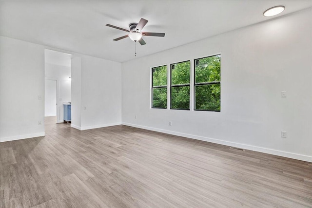 spare room with baseboards, wood finished floors, a ceiling fan, and visible vents