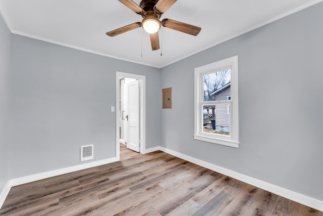 unfurnished room featuring a ceiling fan, baseboards, visible vents, crown molding, and wood finished floors