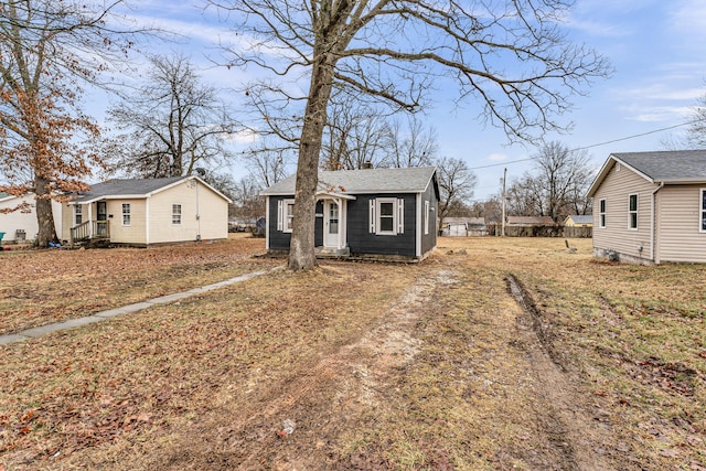 bungalow-style house featuring roof with shingles and an outdoor structure