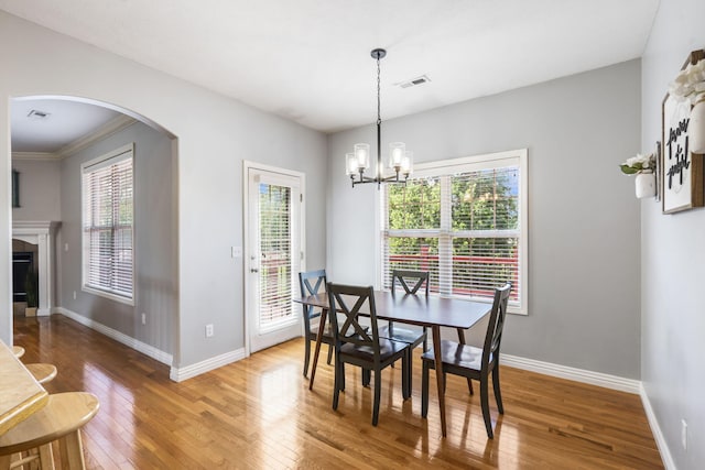 dining room with an inviting chandelier, visible vents, baseboards, arched walkways, and hardwood / wood-style flooring