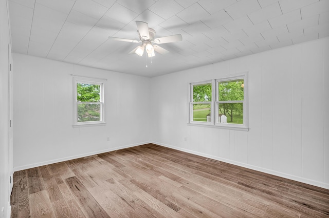 spare room featuring baseboards, visible vents, ceiling fan, and wood finished floors