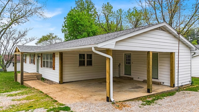 exterior space featuring roof with shingles and a carport