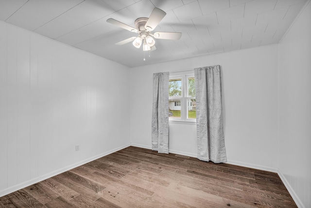 empty room featuring wood finished floors, baseboards, and ceiling fan
