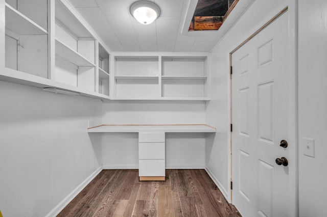 unfurnished office with baseboards, dark wood finished floors, and built in study area