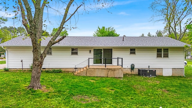 back of property with a yard, roof with shingles, and central AC