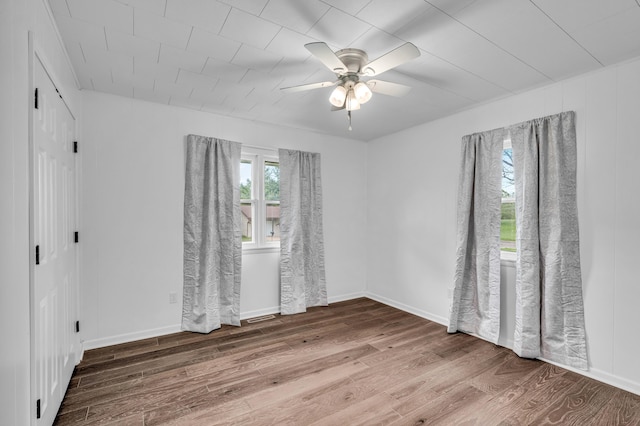 empty room with visible vents, wood finished floors, and ceiling fan