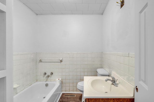 full bathroom featuring toilet, tile walls, vanity, wainscoting, and a bath