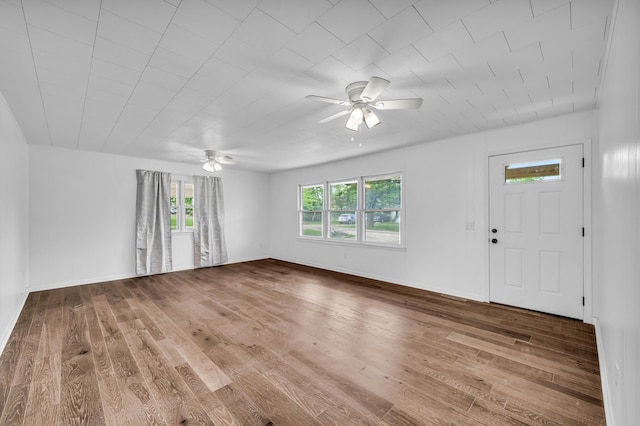 unfurnished living room with baseboards, hardwood / wood-style floors, a ceiling fan, and a healthy amount of sunlight