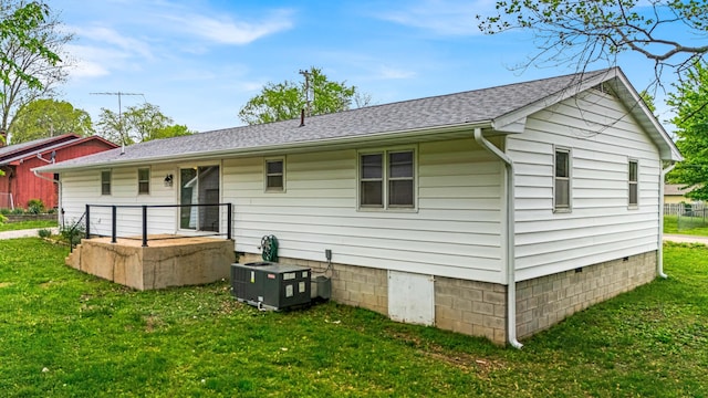 rear view of property with central air condition unit, roof with shingles, crawl space, and a lawn