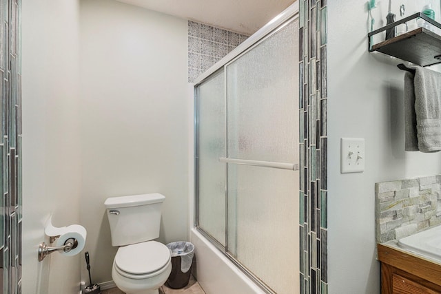 bathroom with toilet and shower / bath combination with glass door