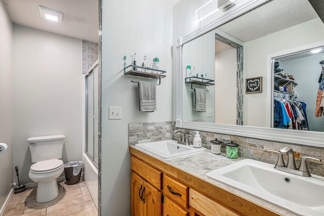 full bath featuring toilet, tasteful backsplash, double vanity, and a sink