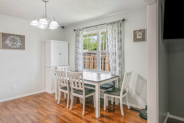 dining room with a notable chandelier, baseboards, and wood finished floors