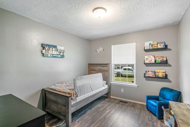 bedroom featuring a textured ceiling, baseboards, visible vents, and wood finished floors