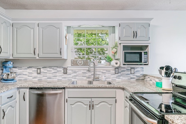 kitchen with decorative backsplash, appliances with stainless steel finishes, and a sink