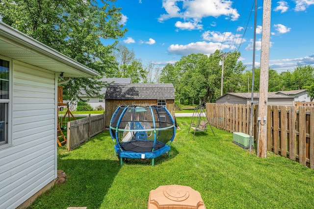 view of yard with a storage shed, a trampoline, an outbuilding, and a fenced backyard