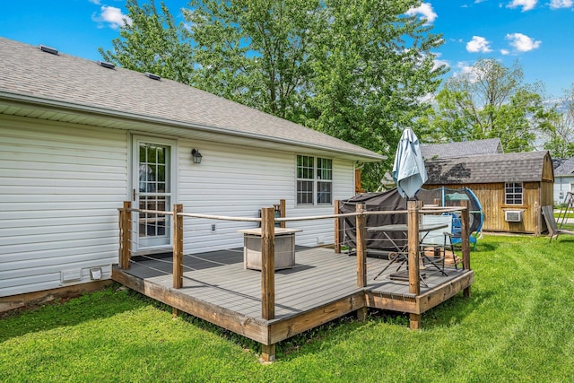 wooden deck with a yard, an outdoor structure, and a storage unit