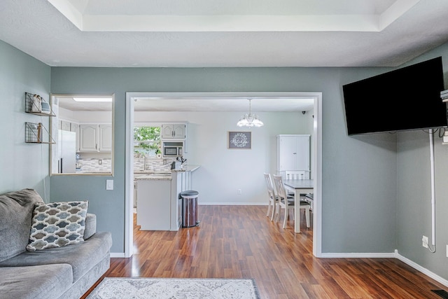 living room featuring baseboards, dark wood finished floors, and an inviting chandelier