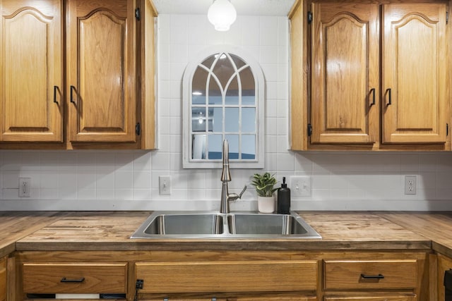 kitchen with wood counters, brown cabinetry, tasteful backsplash, and a sink