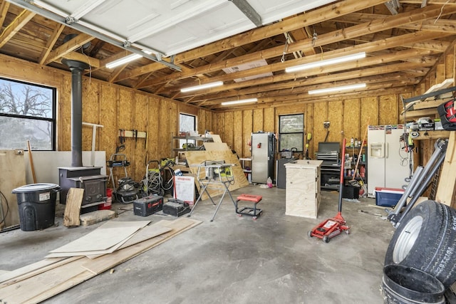 garage featuring a wood stove, white fridge with ice dispenser, and a workshop area