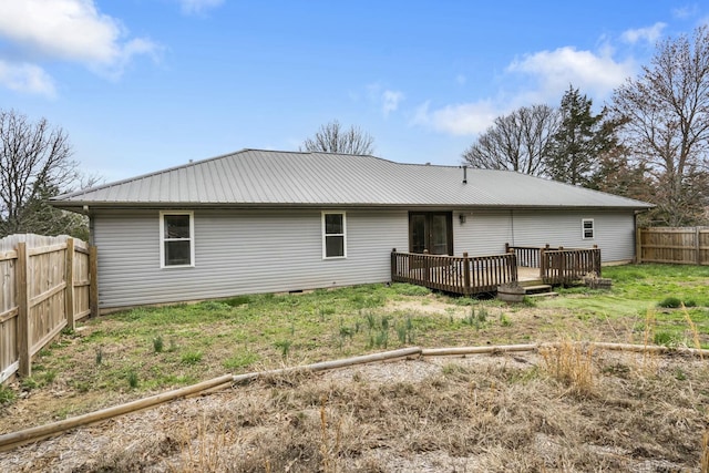 back of house featuring a fenced backyard, a wooden deck, metal roof, and a lawn