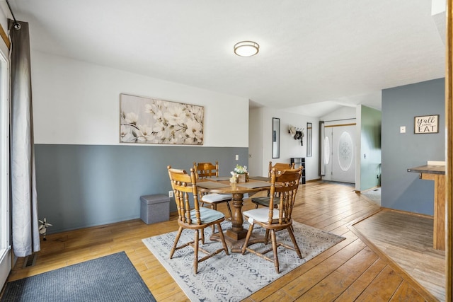 dining space with wood-type flooring and vaulted ceiling