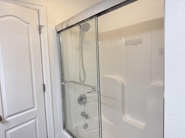 bathroom with bath / shower combo with glass door