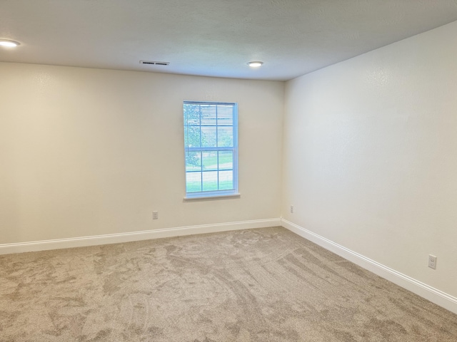 unfurnished room featuring baseboards, visible vents, and carpet