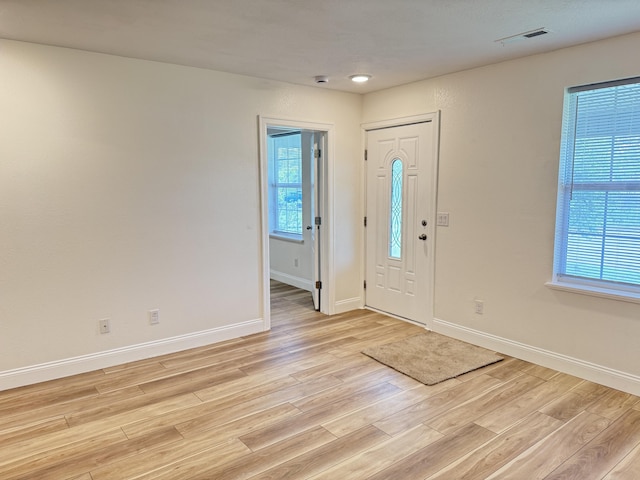 entrance foyer with baseboards, light wood-style floors, and visible vents