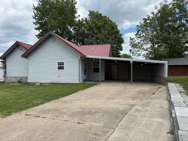 view of front facade featuring a front lawn, concrete driveway, metal roof, and an attached carport