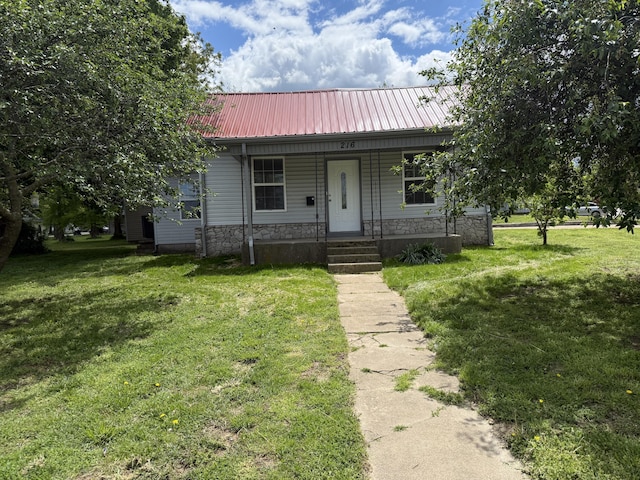 bungalow-style house with metal roof, a porch, a front lawn, and stone siding