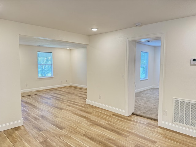 empty room with visible vents, light wood-style flooring, and baseboards