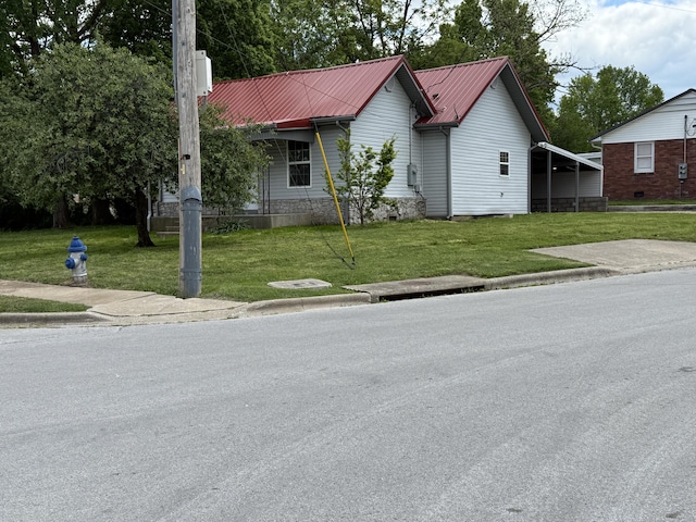 view of front of house featuring metal roof, a chimney, a front yard, and a carport