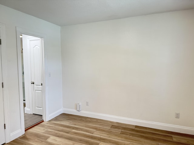 spare room with baseboards and light wood-type flooring