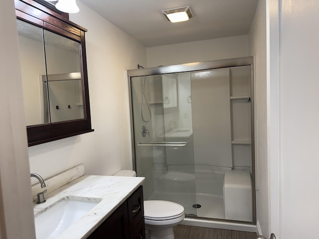 full bath with toilet, wood finished floors, visible vents, a shower stall, and vanity