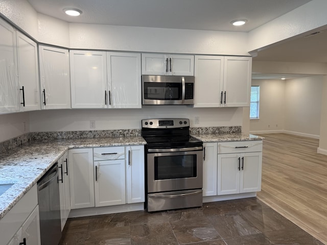kitchen with baseboards, stainless steel appliances, white cabinetry, and light stone countertops
