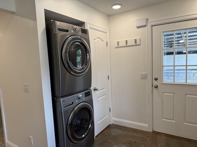laundry area featuring laundry area, stacked washer and clothes dryer, and baseboards