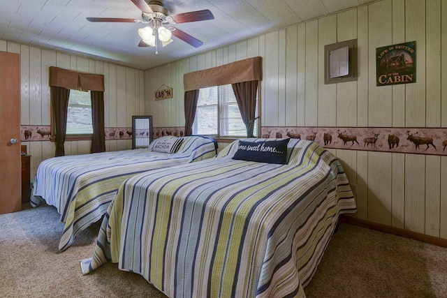 bedroom featuring ceiling fan, wooden walls, and carpet