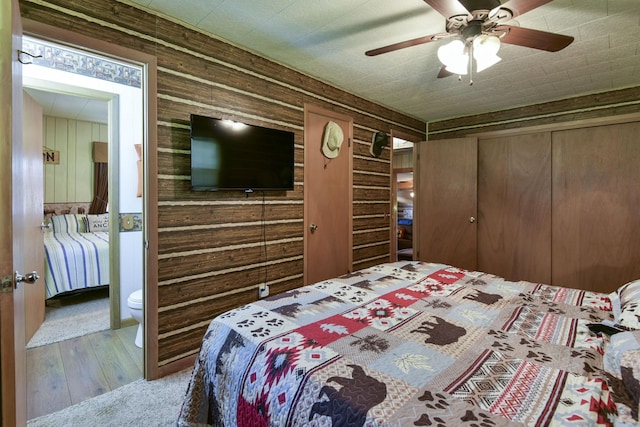 bedroom featuring ceiling fan, wood walls, and wood finished floors