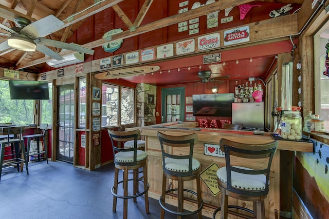 bar with vaulted ceiling, ceiling fan, and a bar