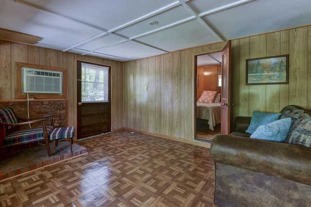 sitting room featuring wood walls, a wall mounted AC, and baseboards