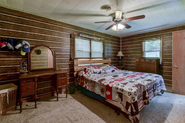 carpeted bedroom with ceiling fan, wooden walls, and visible vents