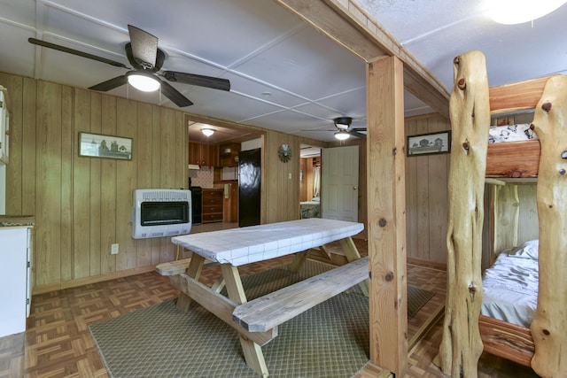 dining space featuring ceiling fan, heating unit, and wood walls