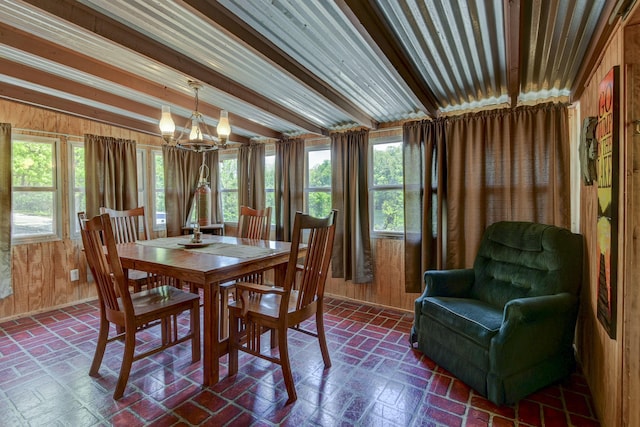 dining area with beam ceiling, wood walls, brick floor, and a notable chandelier
