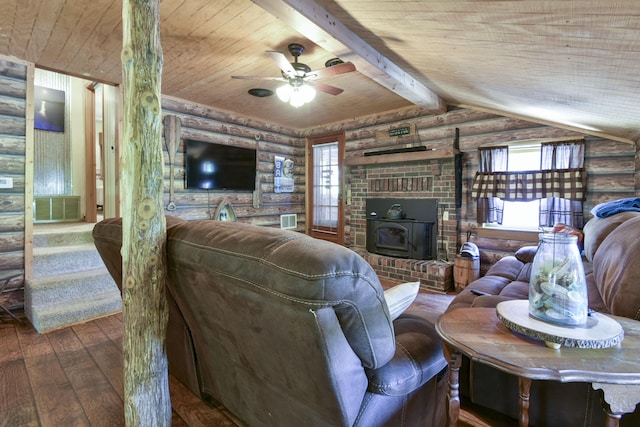living area with a wood stove, plenty of natural light, rustic walls, and hardwood / wood-style flooring